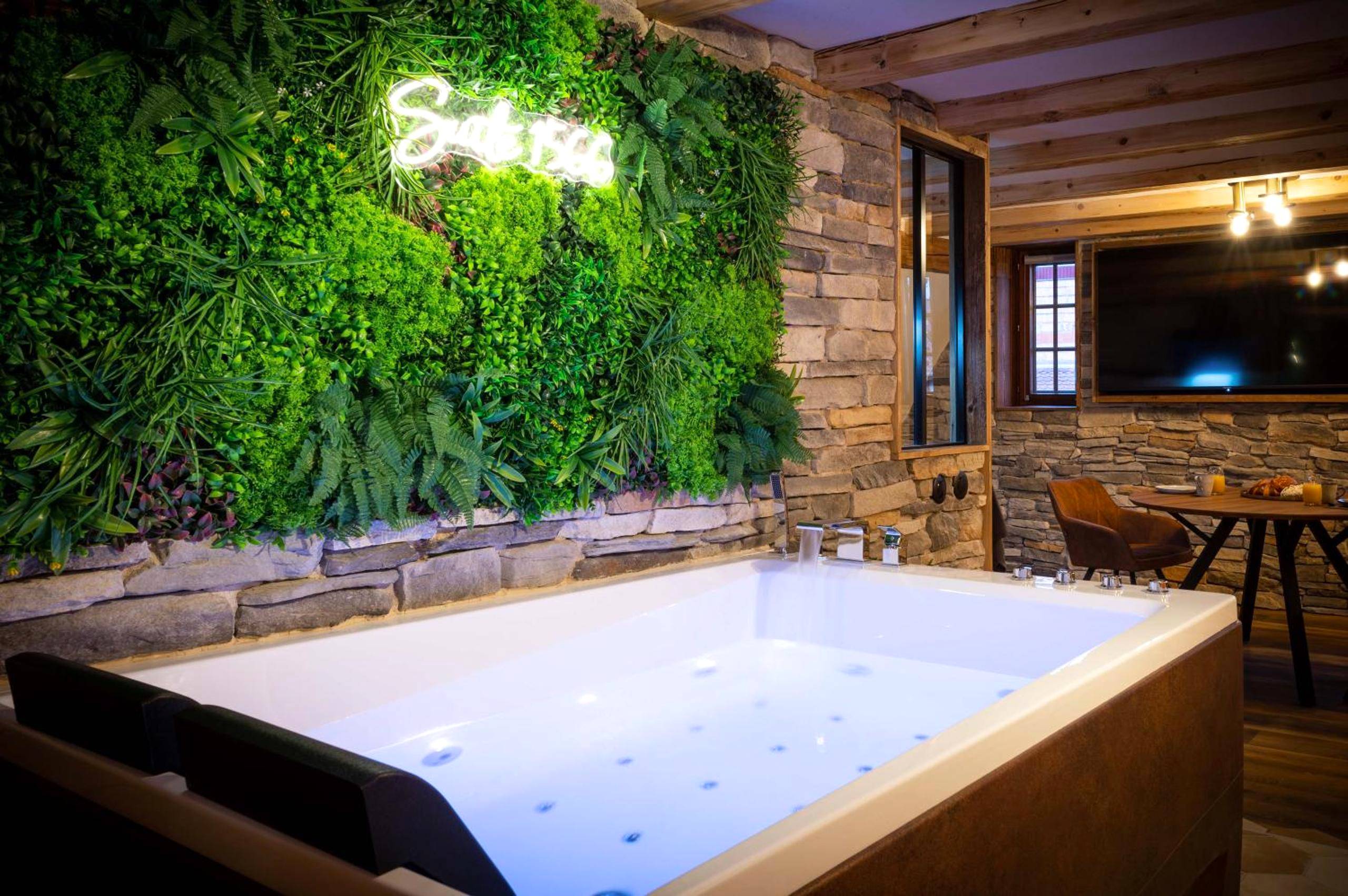 Jacuzzi face à un mur végétal avec néon - Love Room Benfeld - Suite & SPA 1566 Benfeld