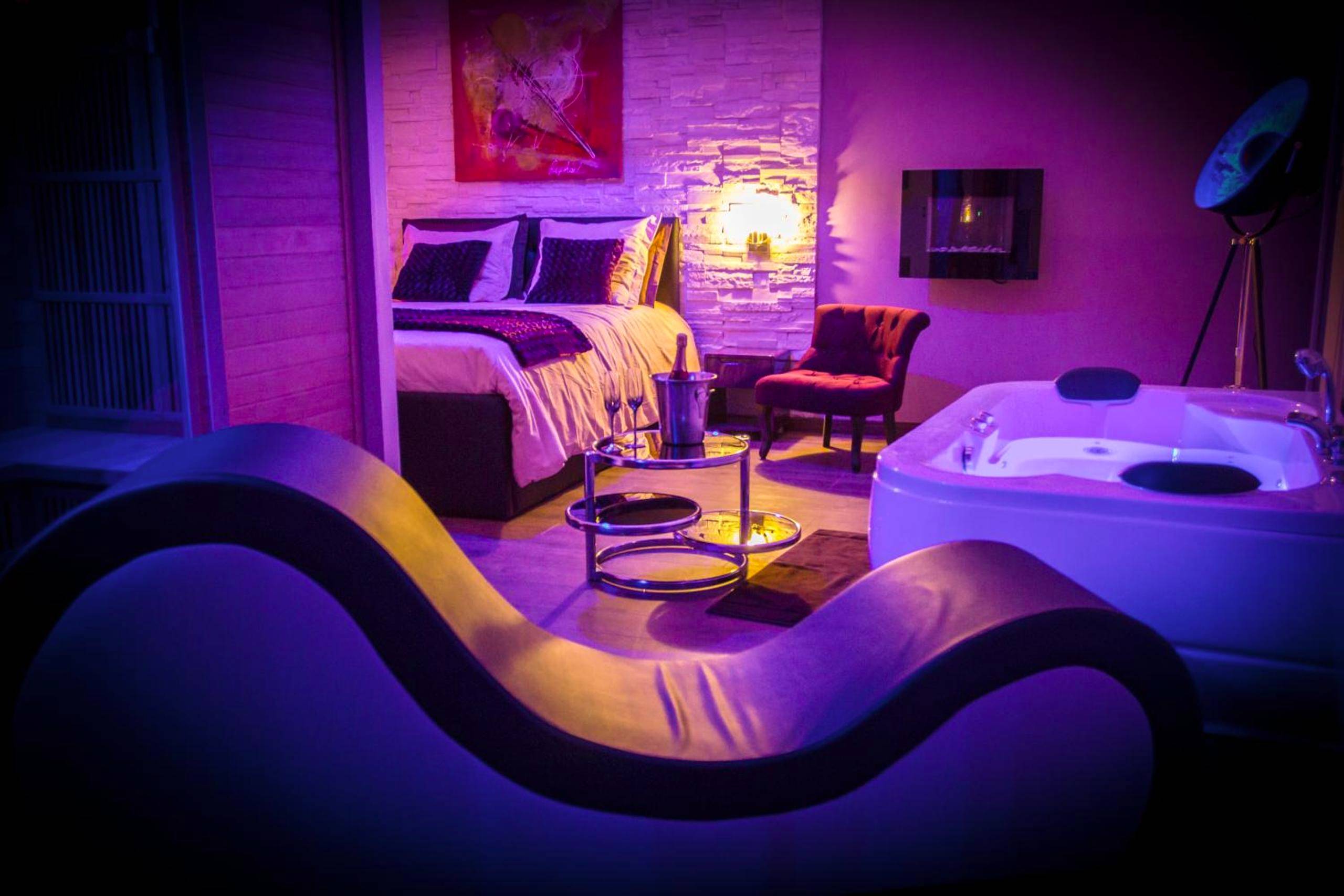 Fauteuil tantrique et jacuzzi sous néons violets - Love Room Dijon - Suite Romantique & Spa