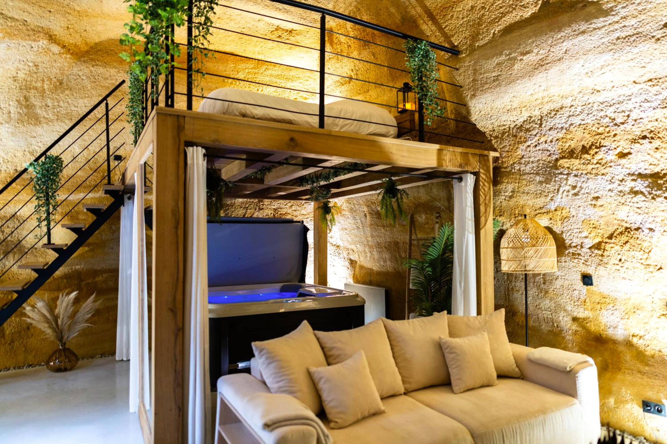 Salon avec canapé face au jacuzzi et mezzanine - Suite troglodyte & spa privé - Luxe et détente