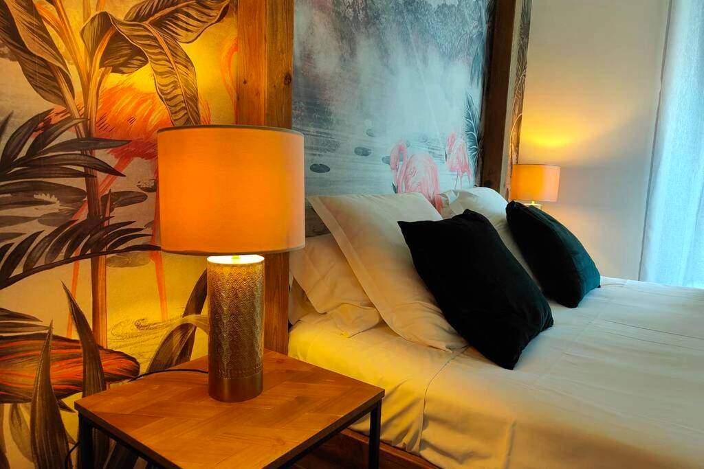 Détail du lit avec lampe et fresque flamants - Suites JM - Le temps d'une Escale (Jacuzzi & Vue Mer)