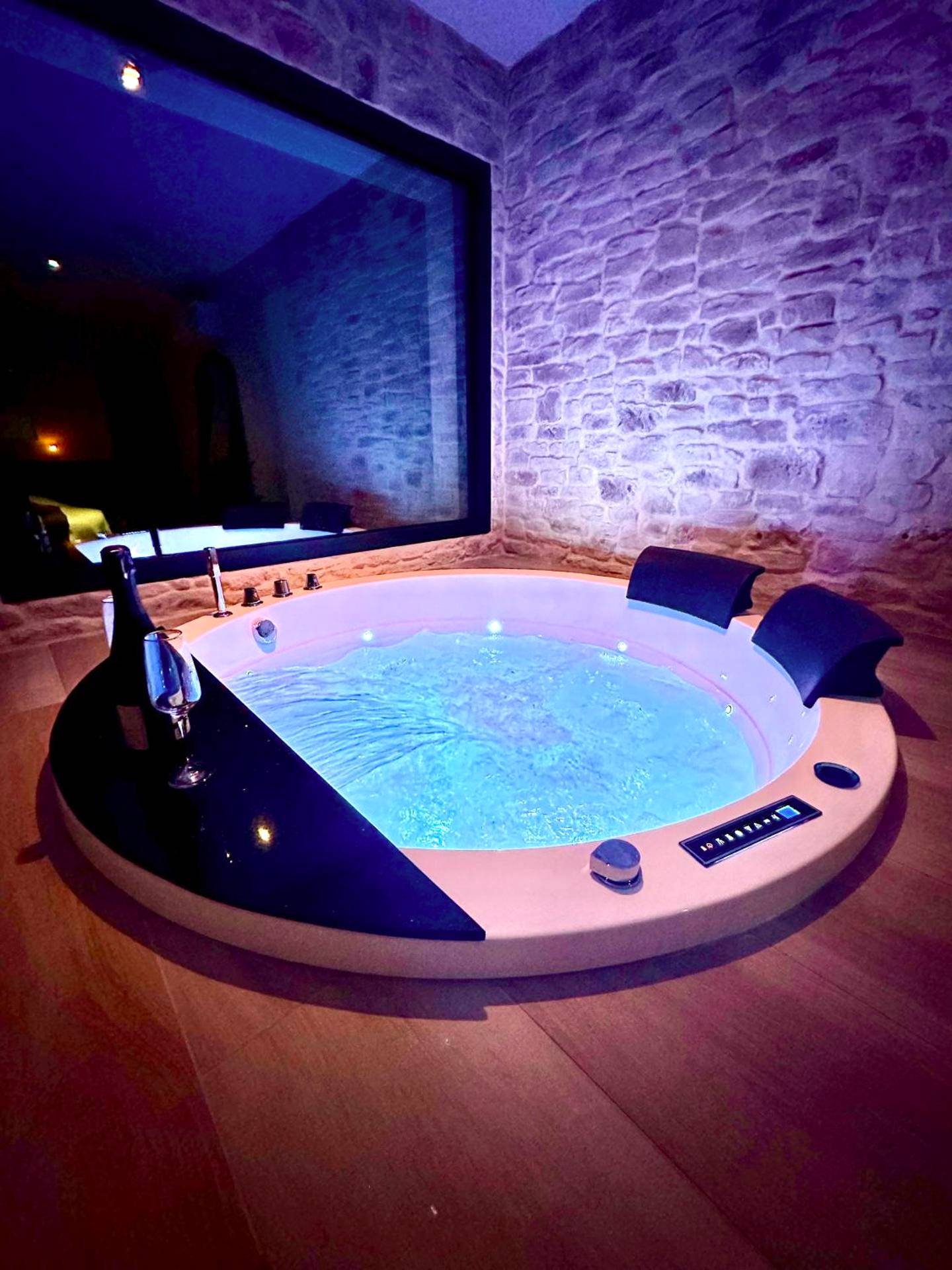 Jacuzzi rond avec éclairage bleu et mur en pierre - Love Room Talmont - Saint - Hilaire - Les Suites du Payré - Suite Romance