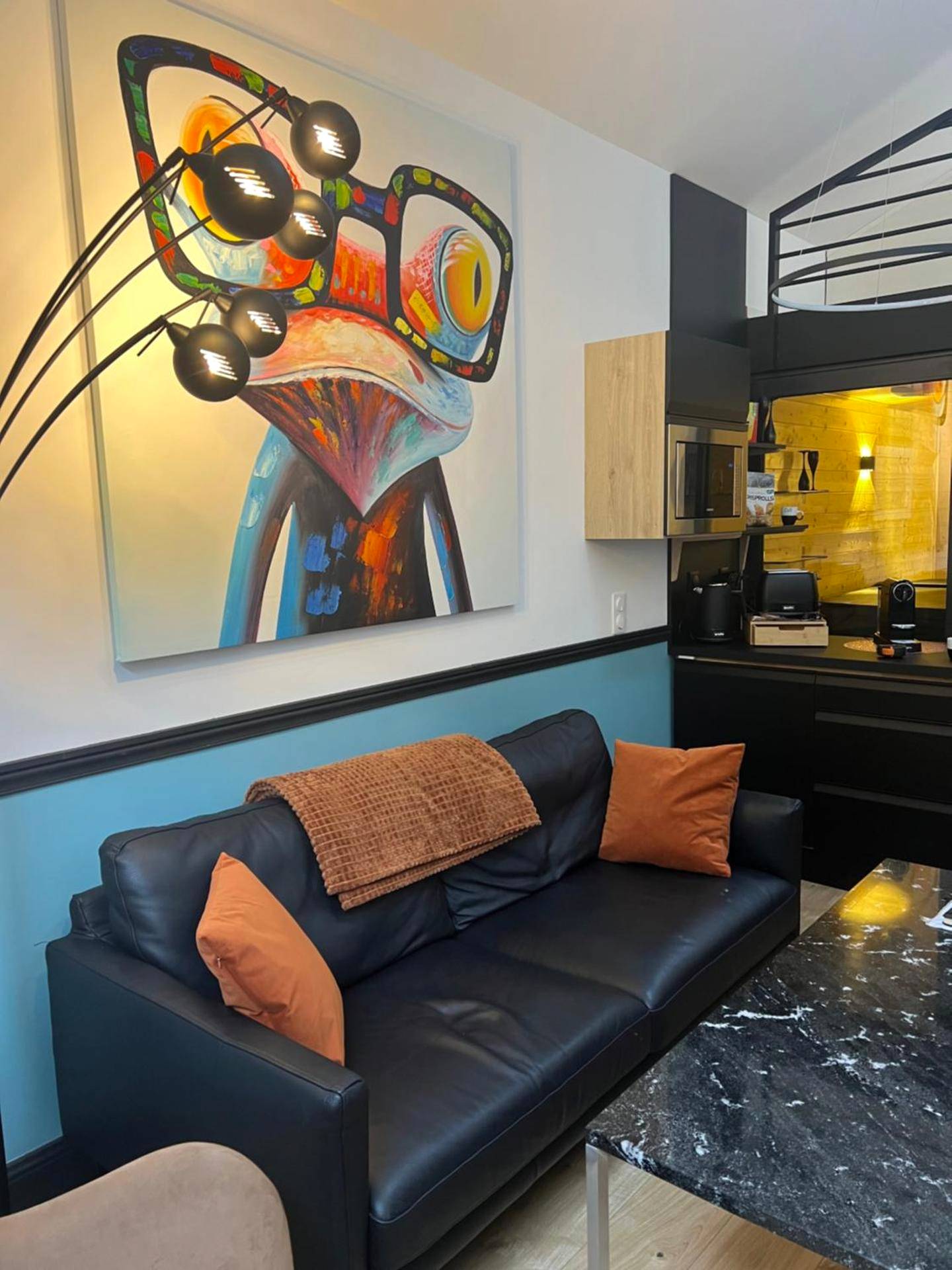Salon moderne avec canapé noir et tableau coloré - Les suites de Stanislas jacuzzi & spa