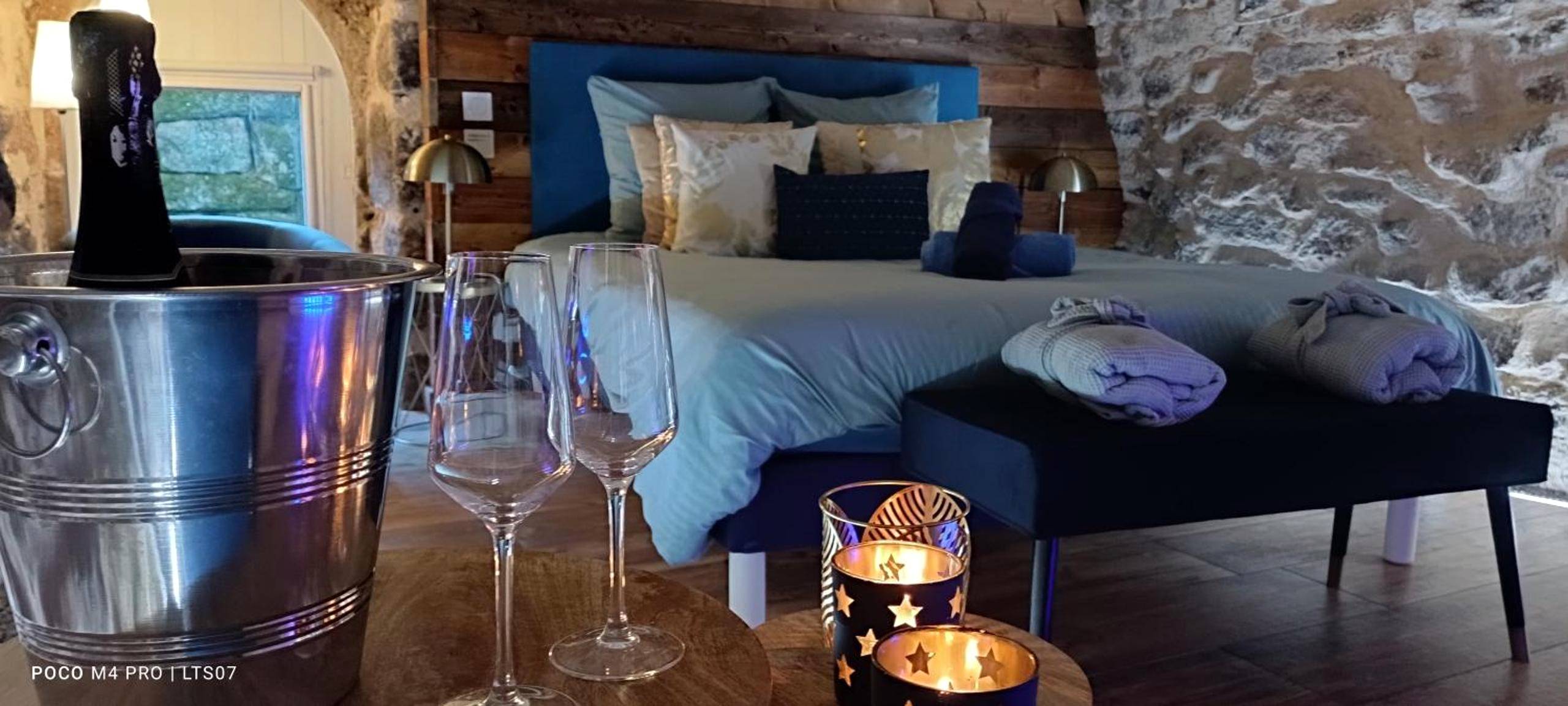 Champagne et bougies face au lit douillet - Le Temps Suspendu