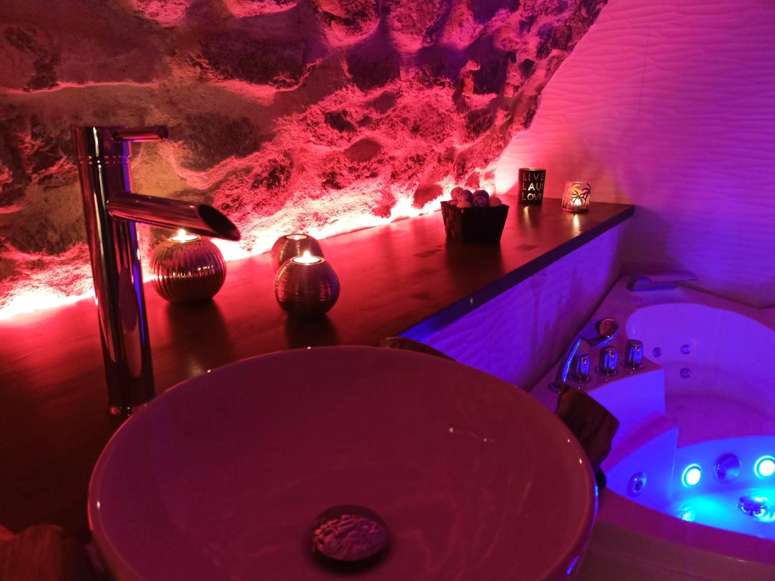 Jacuzzi et vasque sous éclairage rose tamisé - Le Temps Suspendu