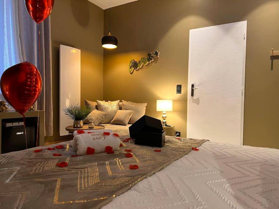 Lit avec pétales de rose et ballons rouges - Love Room Jujurieux - Loving room cocooning avec jacuzzi « la terre »