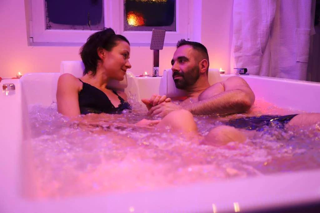 Couple se relaxant dans un jacuzzi éclairé - Love room Unique - Sauna / Jacuzzi