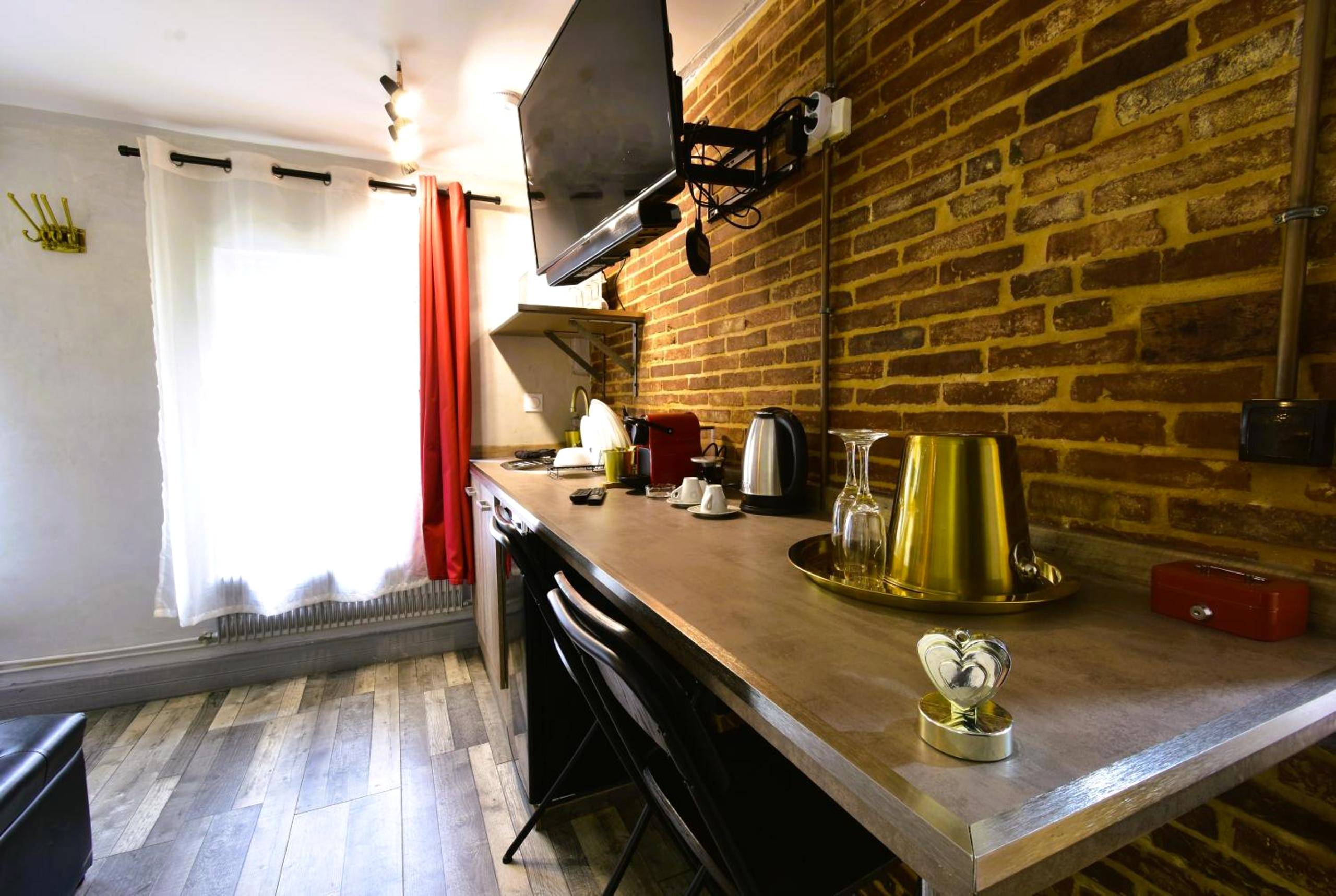 Espace cuisine avec mur en briques et télévision - Appartement jacuzzi privatif : Urban Love