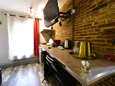 Espace cuisine avec mur en briques et télévision - Appartement jacuzzi privatif : Urban Love