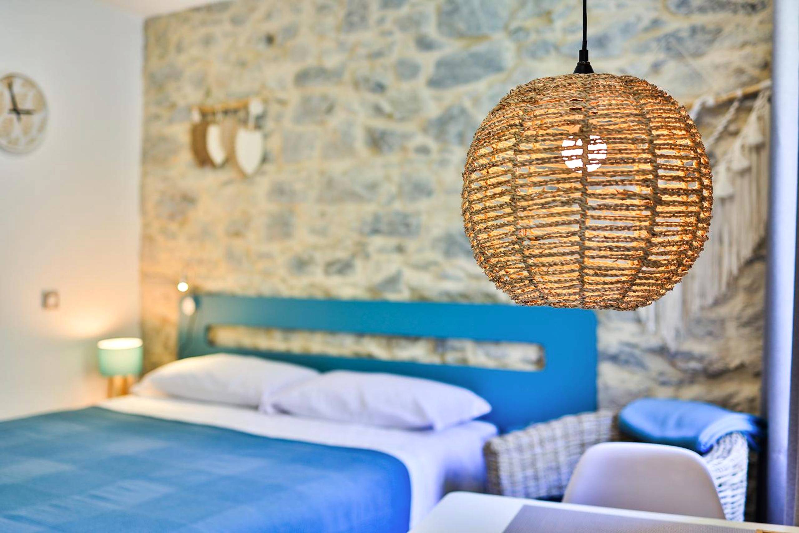 Chambre avec mur en pierre et luminaire tressé - Le Vallaya Suites & Spa
