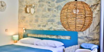 Chambre avec mur en pierre et luminaire tressé - Le Vallaya Suites & Spa