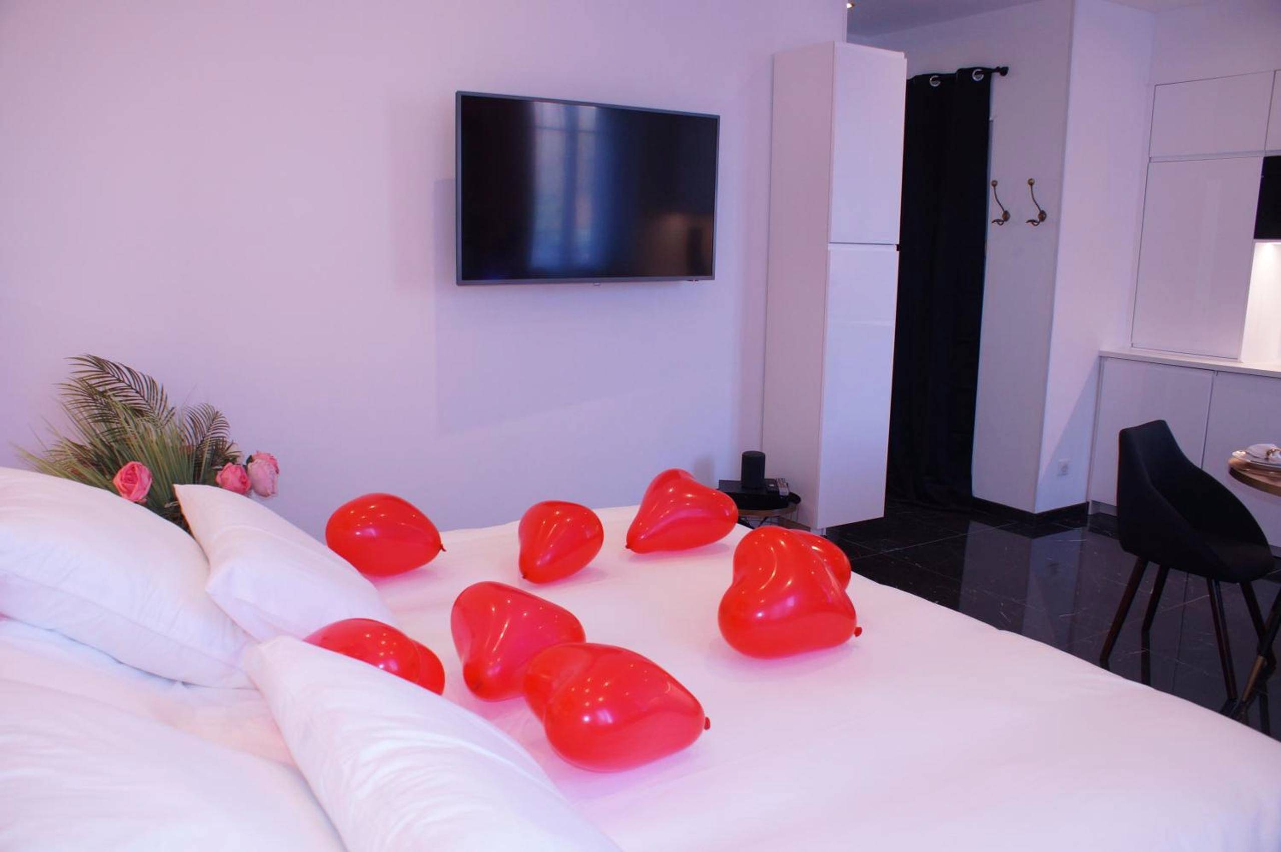 Ballons rouges en forme de cœur sur le lit - Le Vénus - Appartement SPA Privatif Balnéo Sauna