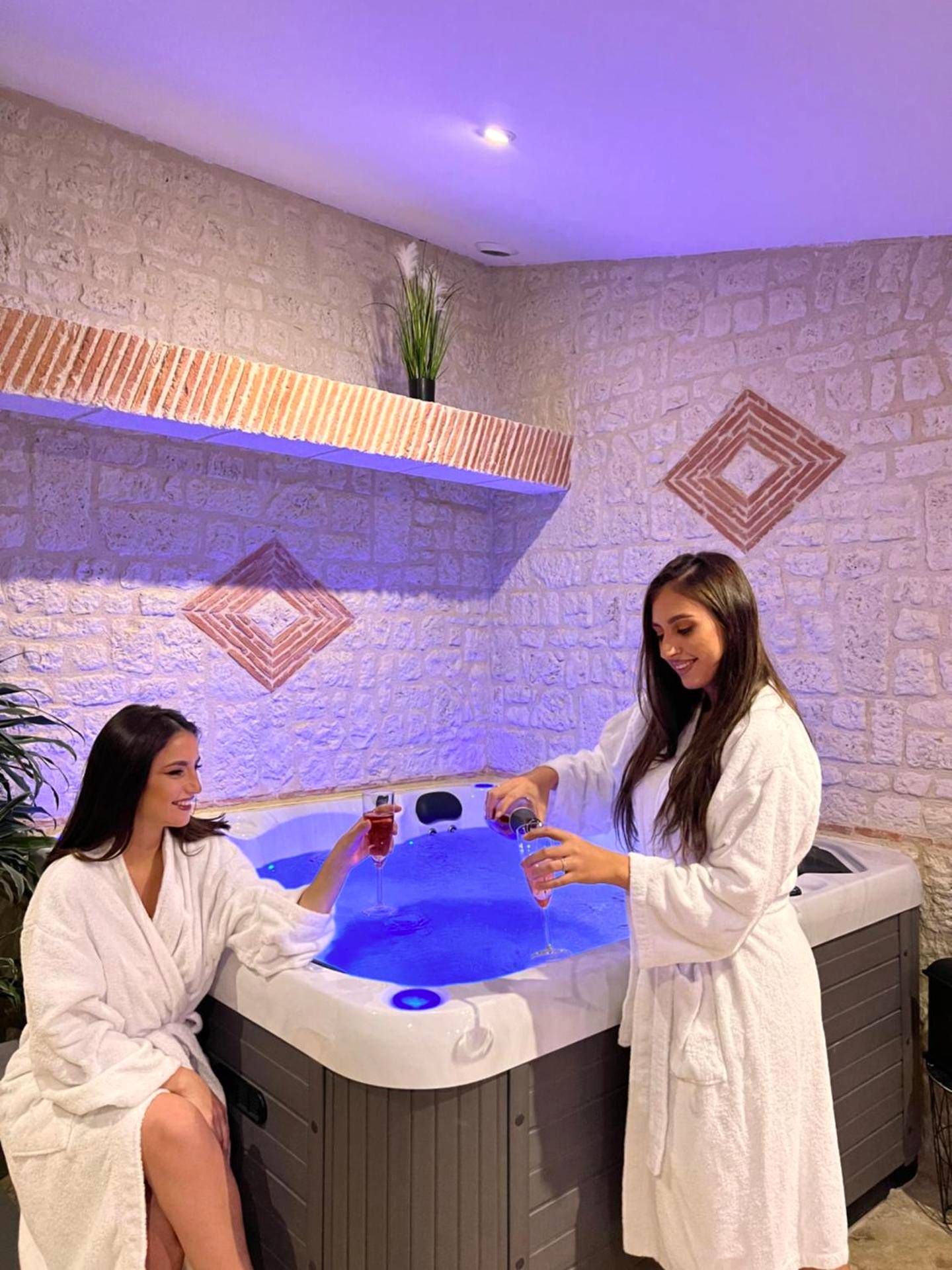 Jacuzzi intérieur et mur en pierres apparentes - Love Room Saint - Nexans - Suite Privative Jacuzzi Sauna de la Villa...