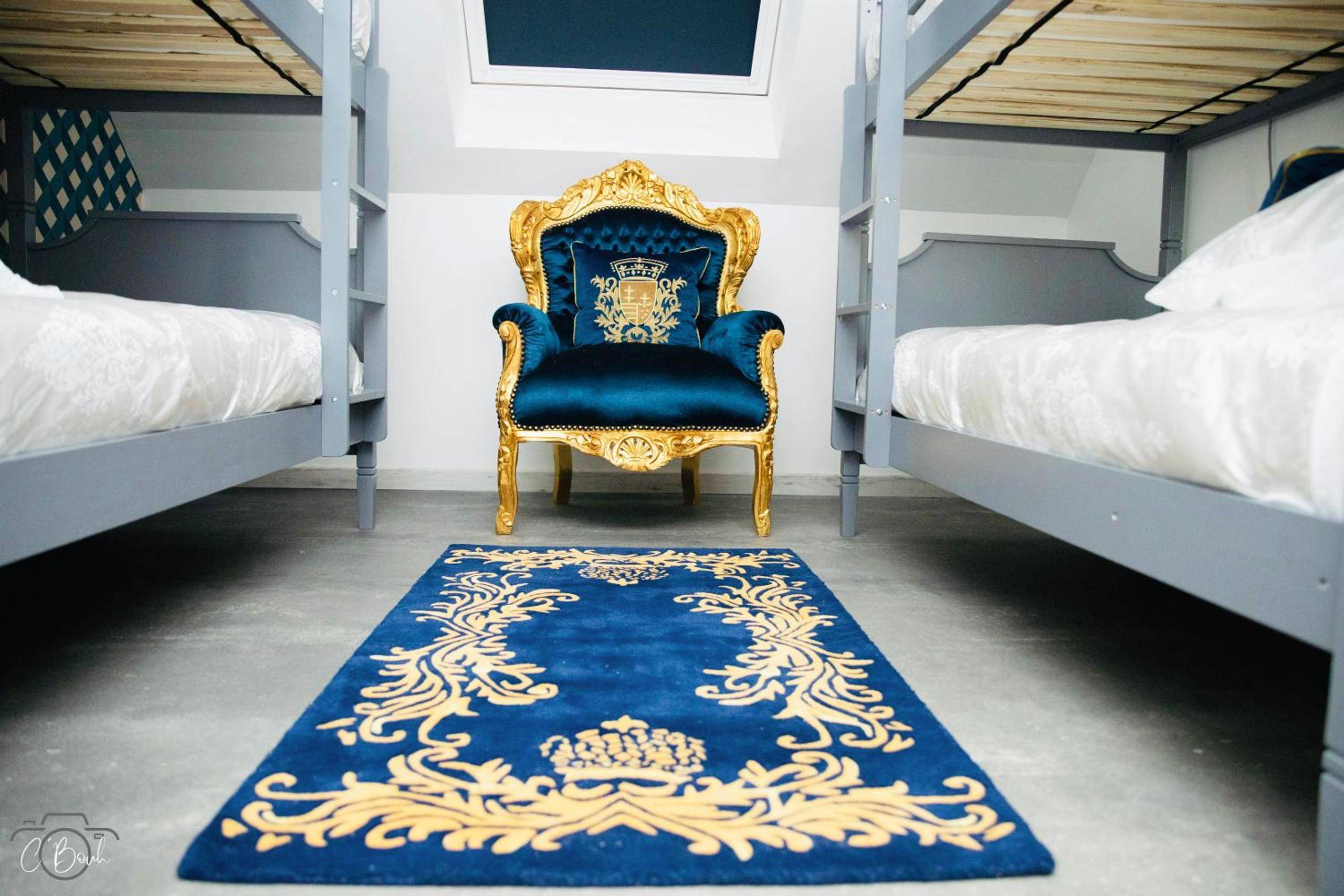 Fauteuil baroque bleu et or entre lits superposés - La Villa des Secrets