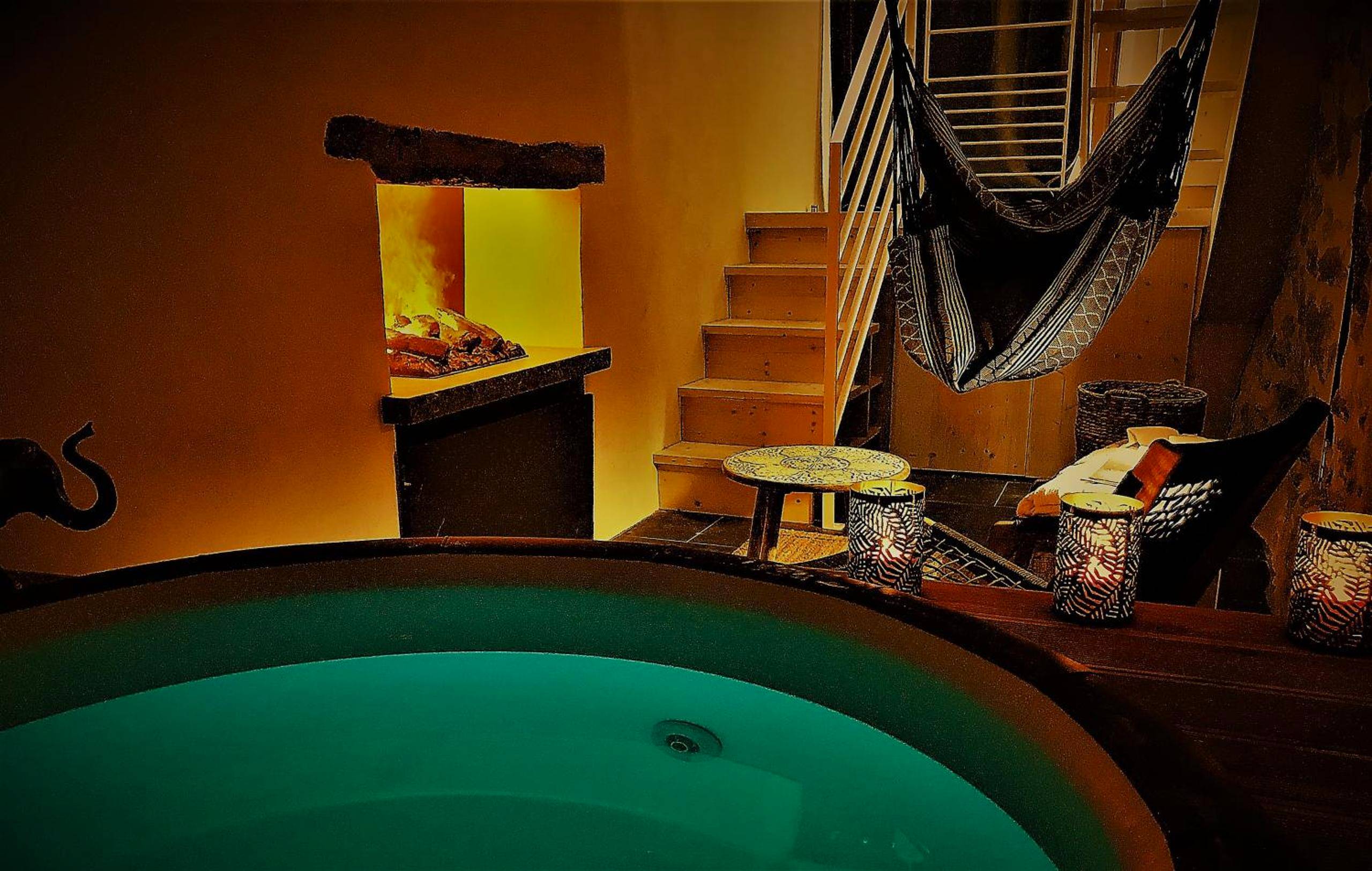 Bain à remous éclairé face à une cheminée - Au Vingtain - Appartement & Spa atypique