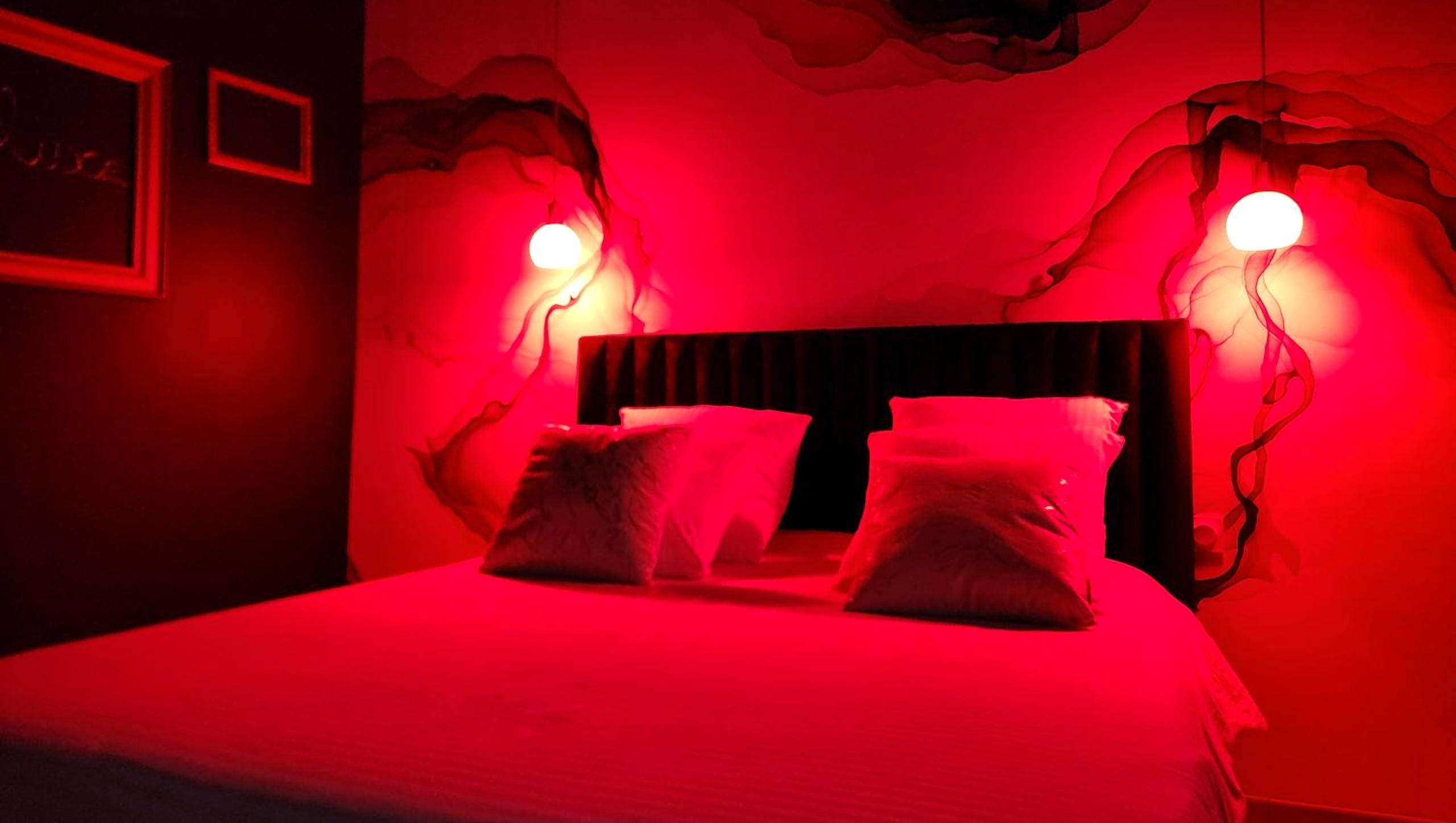 Lit double sous lumière d'ambiance rouge - La Volupté - Love room avec Jacuzzi - Sauna