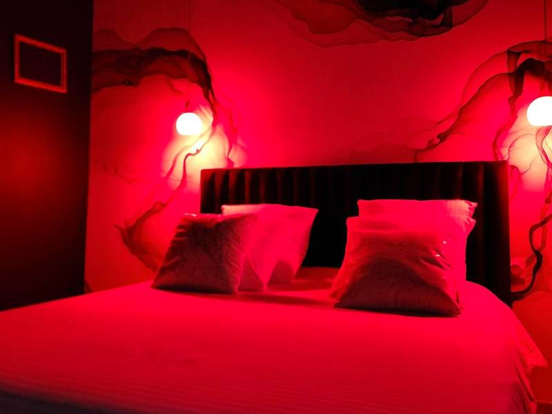 Lit double sous lumière d'ambiance rouge - La Volupté - Love room avec Jacuzzi - Sauna