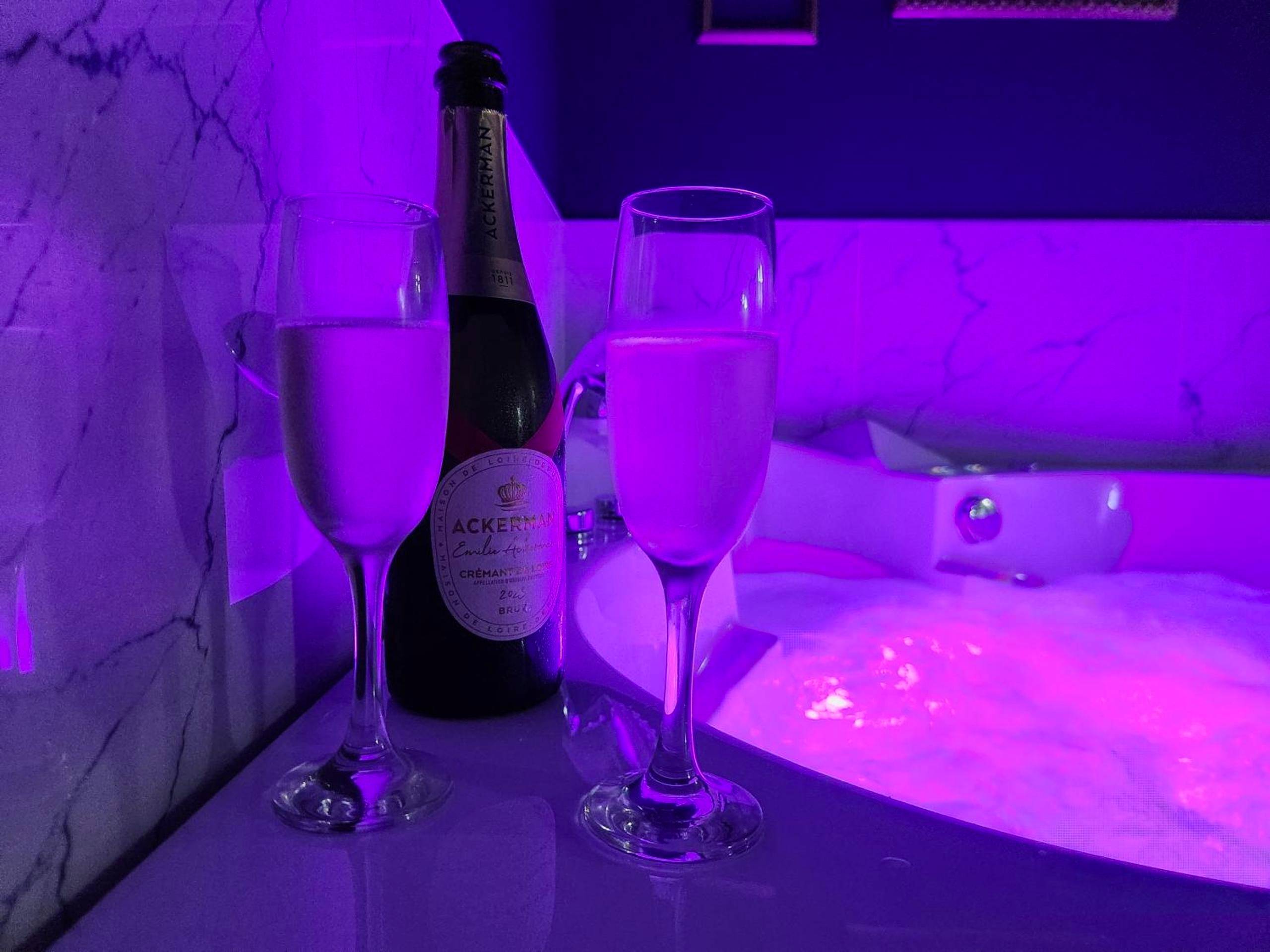 Bouteille et flûtes au bord du jacuzzi - La Volupté - Love room avec Jacuzzi - Sauna