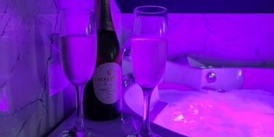 Bouteille et flûtes au bord du jacuzzi - La Volupté - Love room avec Jacuzzi - Sauna
