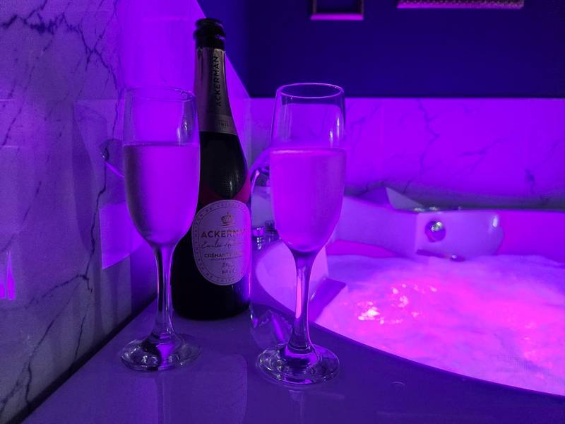 Bouteille et flûtes au bord du jacuzzi - La Volupté - Love room avec Jacuzzi - Sauna