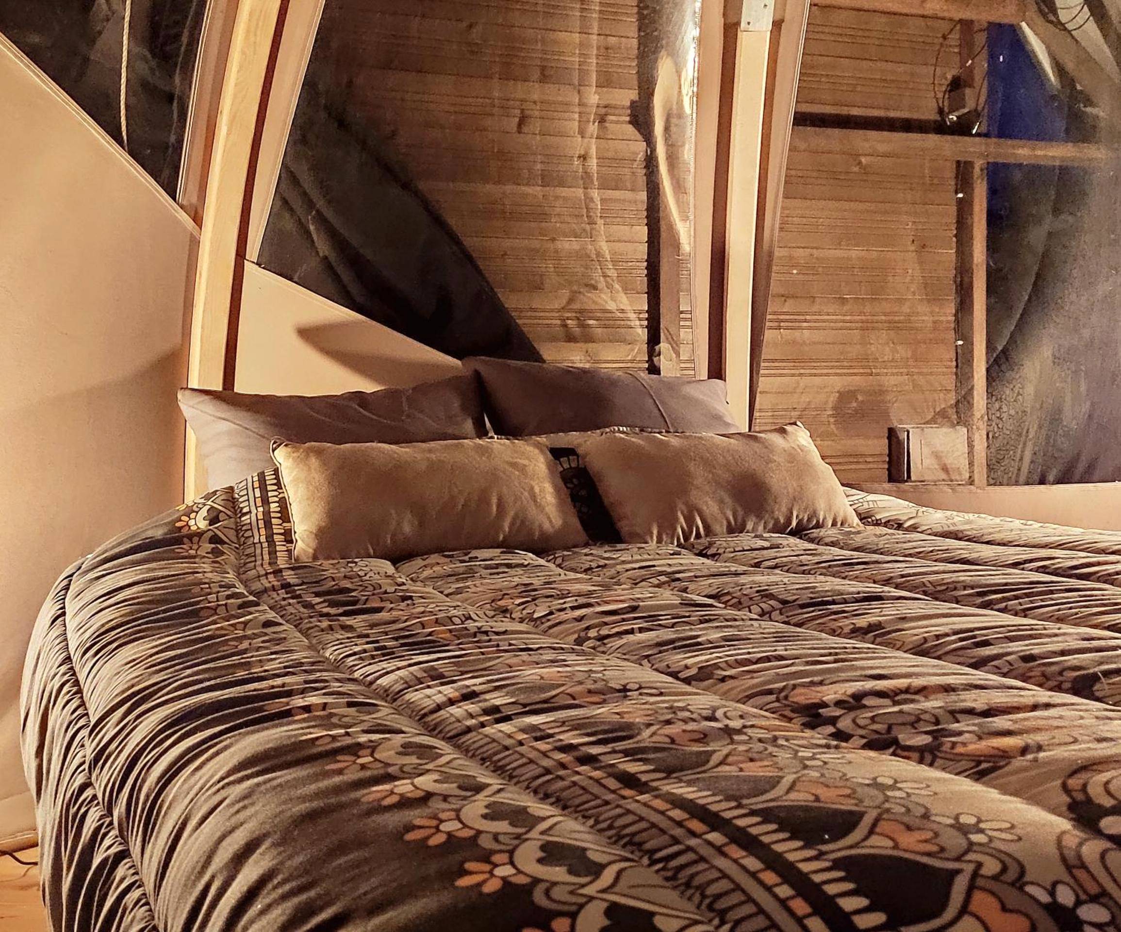 Lit double avec couette à motifs sous le dôme - Le Wigwam du Fassac