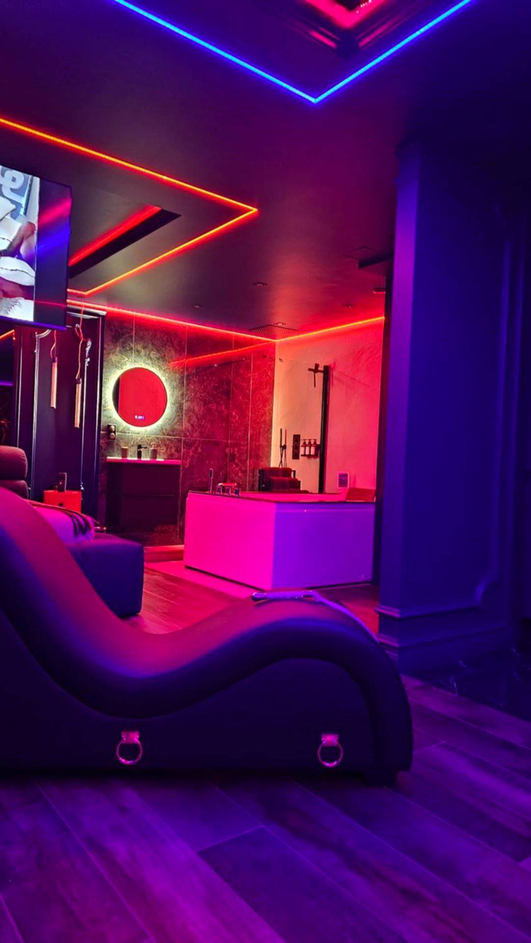 Fauteuil tantrique noir sous lumières néon - Love room - Xtase By luxuria Cannes